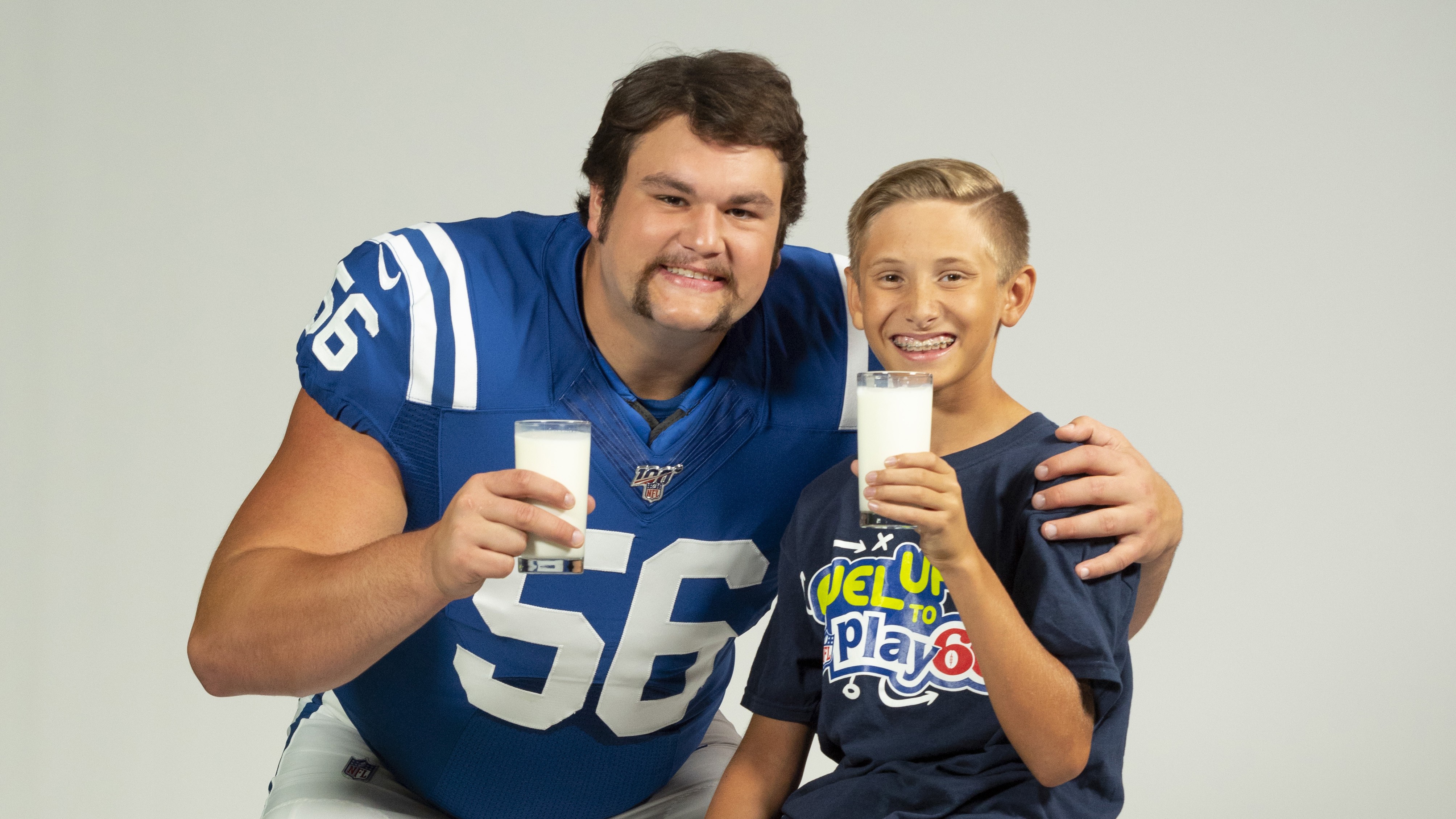 Quenton Nelson smiling with a child in Fuel Up to Play 60 tshirt, both holding glasses of milk
